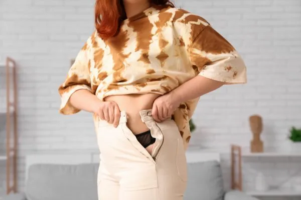 Image of woman trying to do her trousers up after pregnancy weight gain Ladymoor