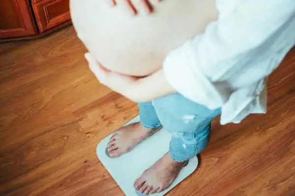 Image of woman weighing herself and experiencing weight gain through pregnancy Ladymoor